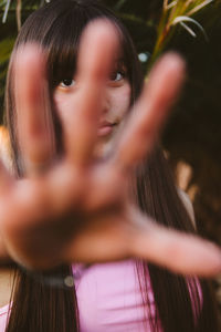 Portrait of teenage girl gesturing against plants