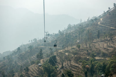 Overhead cable car over mountains against sky