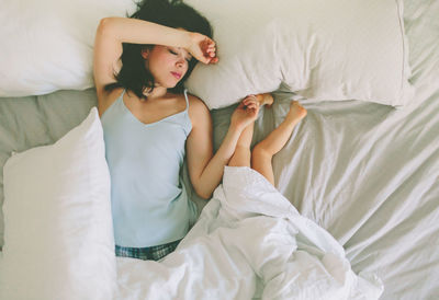 High angle view of mother sleeping with child on bed at home