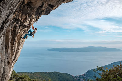 Man climbing mountain against sky