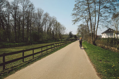 Rear view of girl riding bicycle on footpath