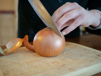 Hand holding vegetables on cutting board