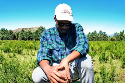 Portrait of man sitting on field against clear sky