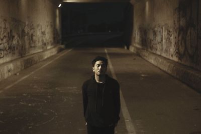 Young man standing on road in city at night