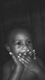 Close-up of thoughtful baby girl covering mouth at home