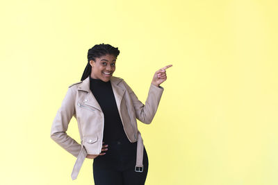 Portrait of young man standing against yellow background