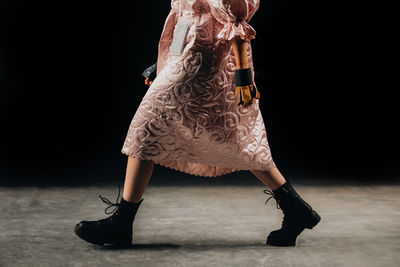 A cropped figure of a fashionable model walking the catwalk in a pink designer outfit
