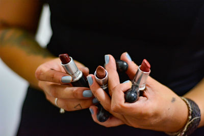 Midsection of woman holding various lipstick