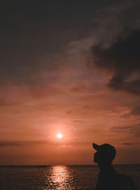 Silhouette person by sea against sky during sunset