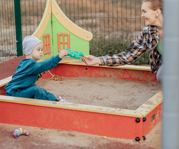 Cute little boy with down syndrome in a funny hat with his mother, swinging on a swing, soap bubbles