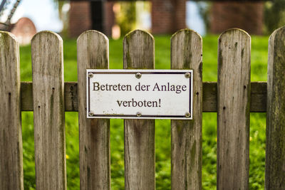 Close-up of warning sign on wooden fence