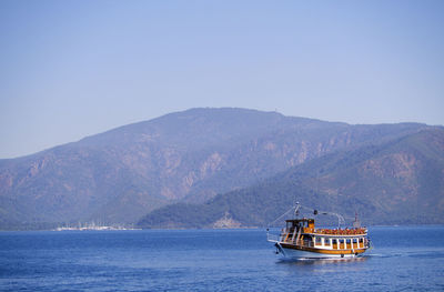 Ship sailing on sea against mountain