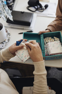 Hands of female student holding sanitary pads and tampons at table in school office