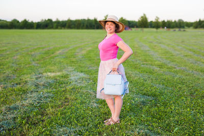 Full length portrait of woman standing on field