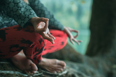 Low section of woman doing yoga on rock