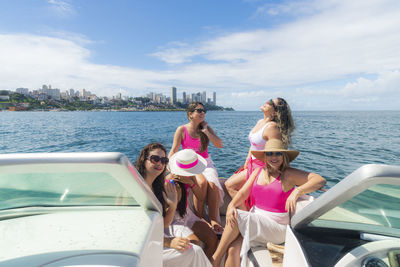 Women in bikini sitting on a boat wearing pink outfit. 