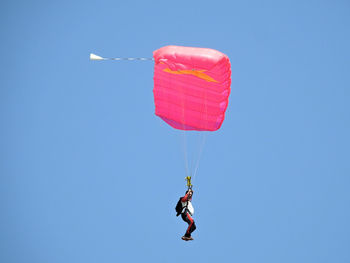 Low angle view of person paragliding against clear blue sky