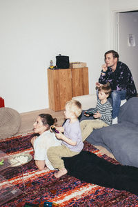 Kids playing video game while sitting with parents at home