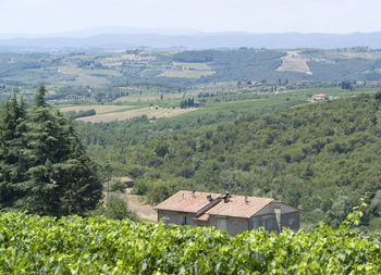 Scenic view of agricultural field by houses and trees against sky