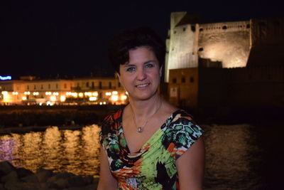 Portrait of smiling beautiful woman against castel dell ovo at night