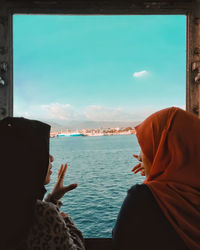 Rear view of woman looking at sea against sky