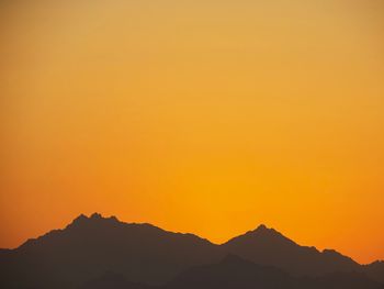 Scenic view of silhouette mountains against orange sky