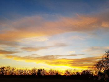 Silhouette trees against dramatic sky during sunset