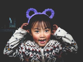 Portrait of cute girl smiling against black background