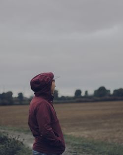 Side view of woman standing on field against sky