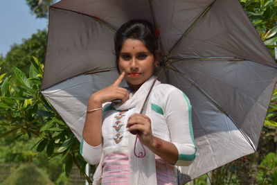 Young woman holding umbrella while standing outdoors