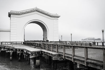 Bridge over river against sky in city