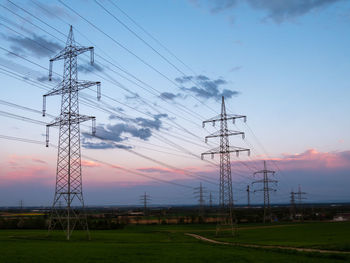 Low angle view of electricity pylon on field against sky