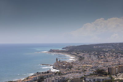 Aerial view of townscape by sea against sky