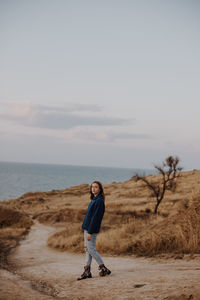 Full length of woman walking on dirt road against sky