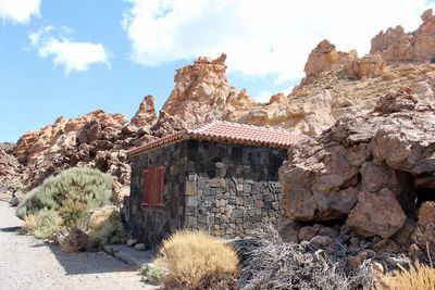 View of old building and rocks against sky