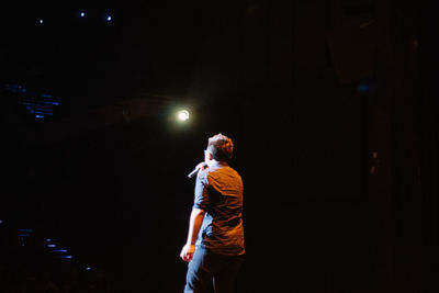 Man standing by illuminated lamp at night