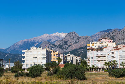 Buildings and mountains against blue sky