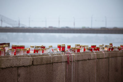 A beautiful red and white candles on the railing of a river side in the foggy riga