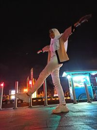 Woman standing on illuminated city against sky at night