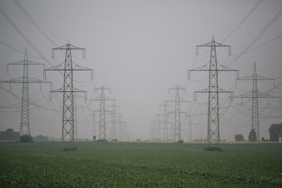 Electricity pylon on field against sky