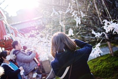 Rear view of woman standing on sunny day during winter