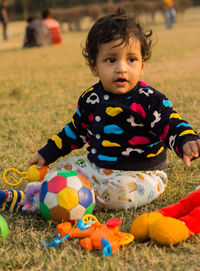 Full length of cute baby boy playing with toys on field