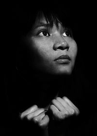 Close-up portrait of young woman against black background