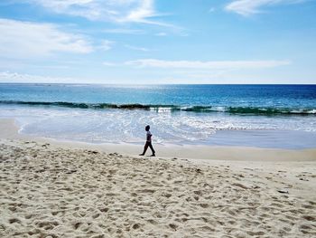 Full length of boy walking on beach against sky