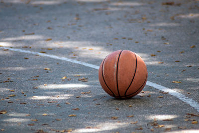 A basketball rests on an outdoor basketball court, ready for someone to play a game