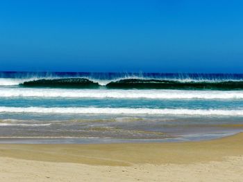 Scenic view of beach against clear blue sky