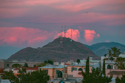 Town by mountain against sky during sunset