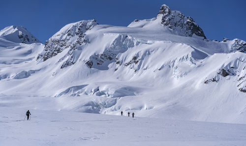 People on snowcapped mountain against sky