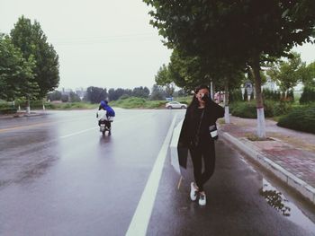 Rear view of woman on road against sky