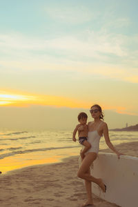 Full length of woman on beach against sky during sunset